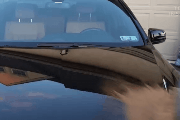 water test on a black car hood treated with ceramic coating, where water rolls off smoothly, demonstrating strong hydrophobic properties and a glossy finish.