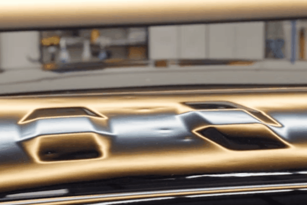 showing several dents on the roof of a black car, highlighted by reflection lines that shift as the camera pans across, emphasizing the extent of hail damage. The distorted reflections make the hail dents clearly visible against the glossy surface.