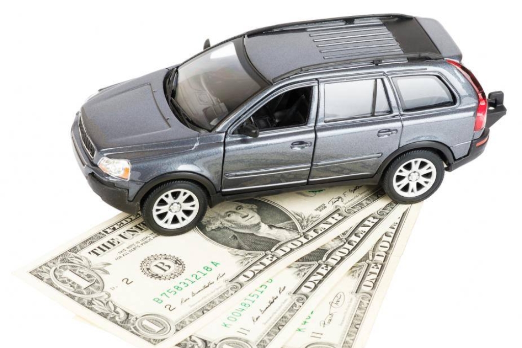 Model SUV parked on top of several U.S. dollar bills, symbolizing the paintless dent repair cost in Colorado Springs and the potential savings compared to traditional bodywork.