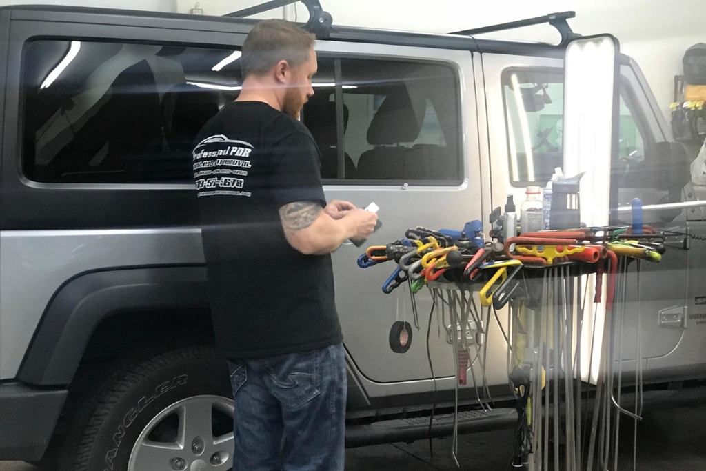 Hail Damage Repair Process captured mid-repair in Colorado Springs, showing a technician from Professional PDR preparing specialized dent removal tools next to a silver SUV. The image highlights the organized setup and hands-on precision involved in paintless dent repair.