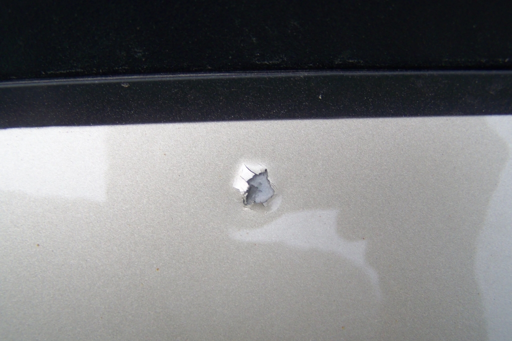Hail Damage Repair Process urgency shown through a close-up of chipped paint exposing bare metal on a vehicle in Colorado Springs. This image highlights the risk of rust and long-term damage when hail-related dents and cracks go unrepaired.