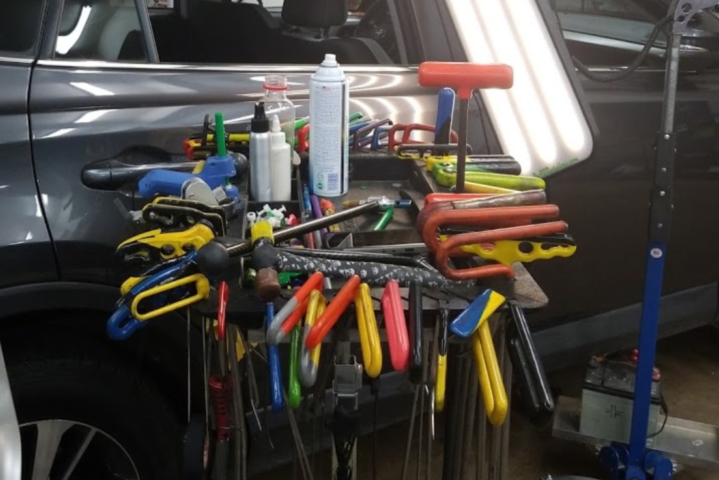 A mobile workstation filled with colorful paintless dent repair tools including metal rods, glue-pulling tabs, knockdown hammers, and polishing sprays, showcasing the specialized tools used in motorcycle dent repair in Colorado Springs.