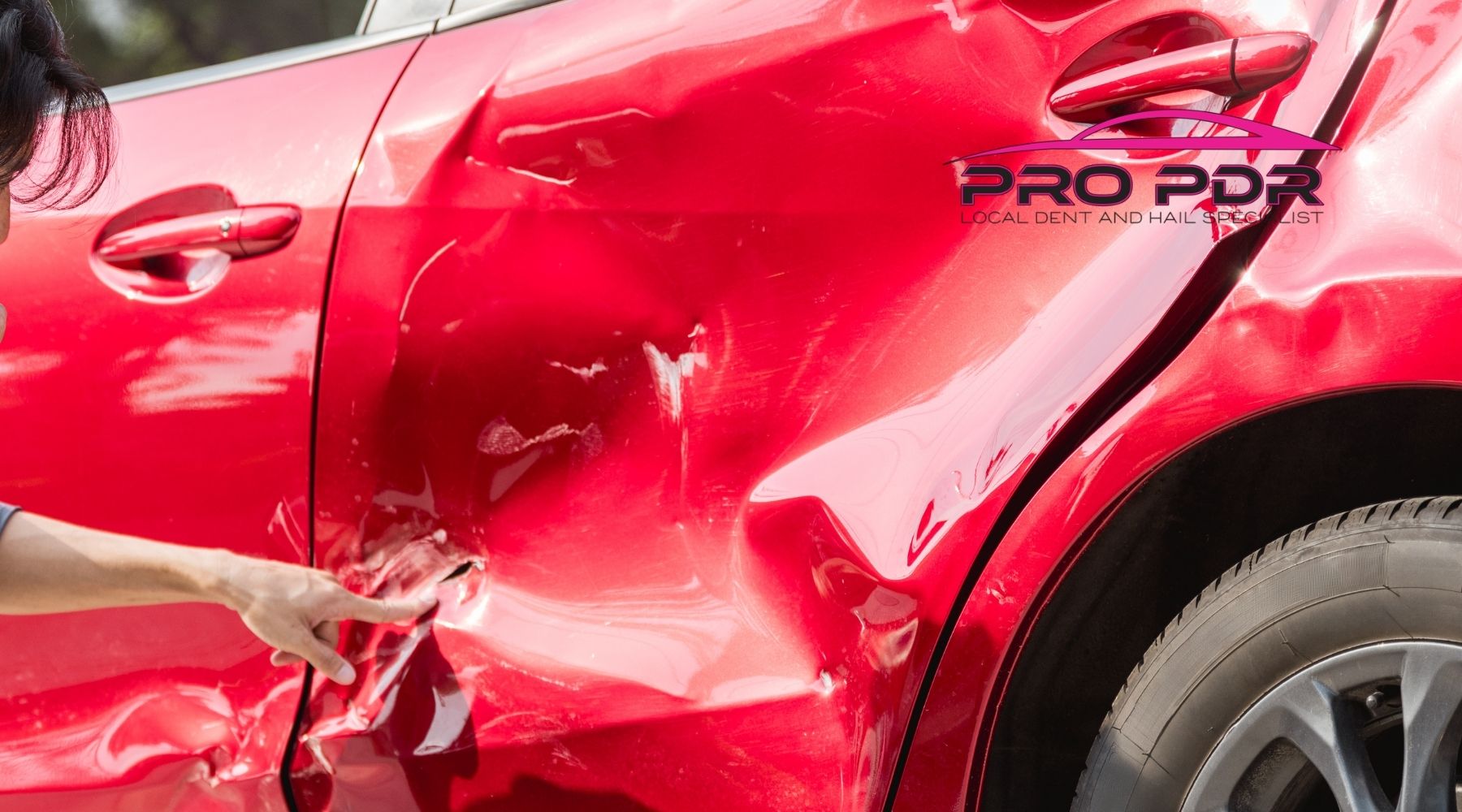Severely dented red car door and rear quarter panel showing collision damage before paintless dent repair