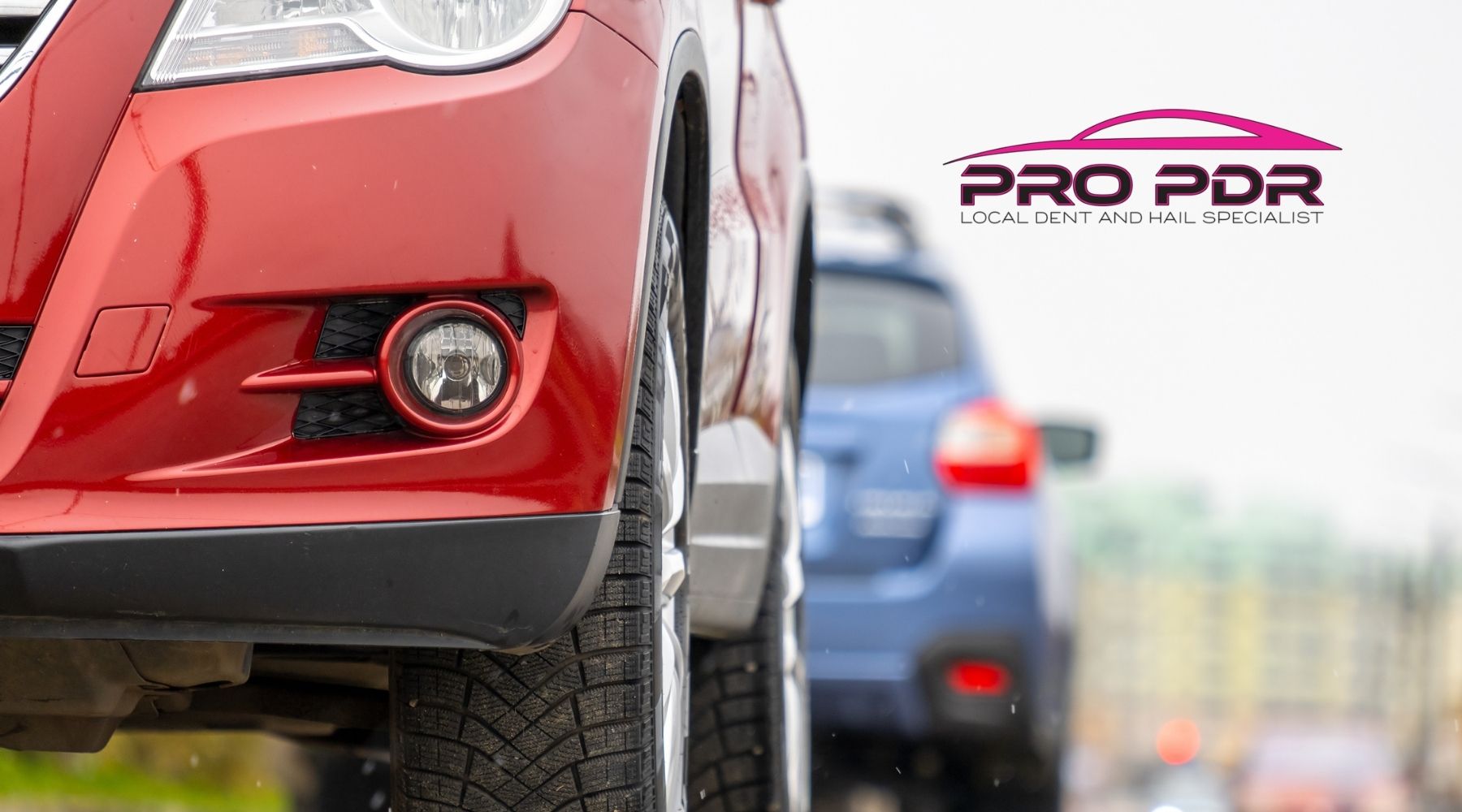 Red SUV in foreground with Pro PDR logo and blurred blue car in background, representing local dent and hail repair services.