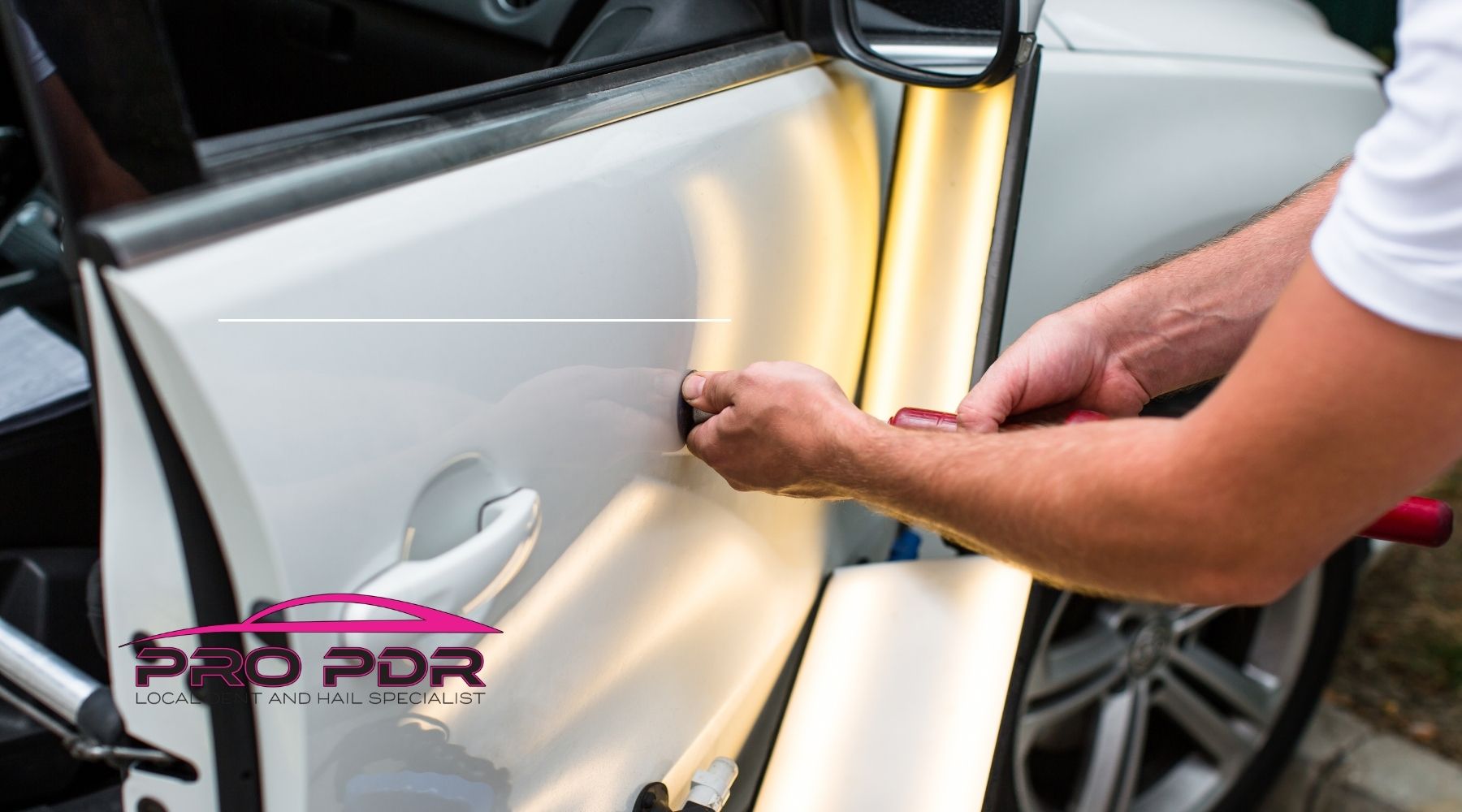 Technician performing paintless dent repair on a white car door using specialized tools