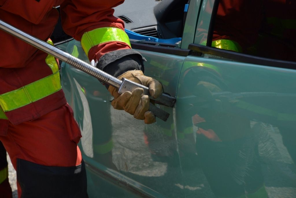 Technician using a dent repair tool on a car door during paintless dent repair