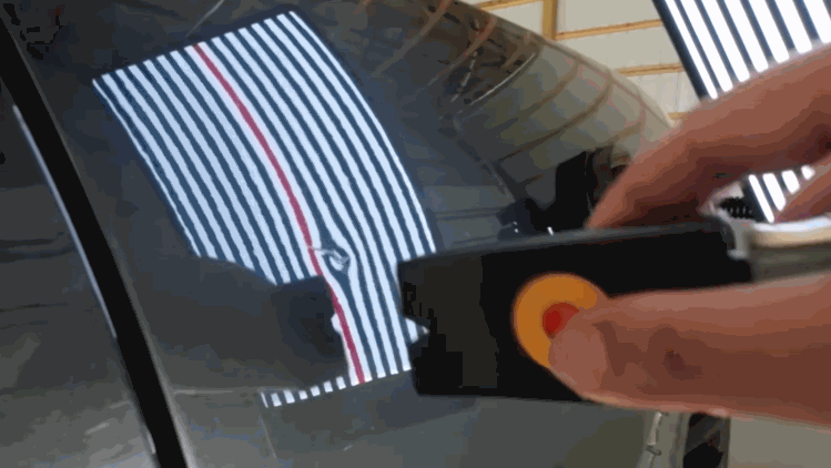 A technician uses a light reflection board to check dents on a dark car panel during hail damage repair.